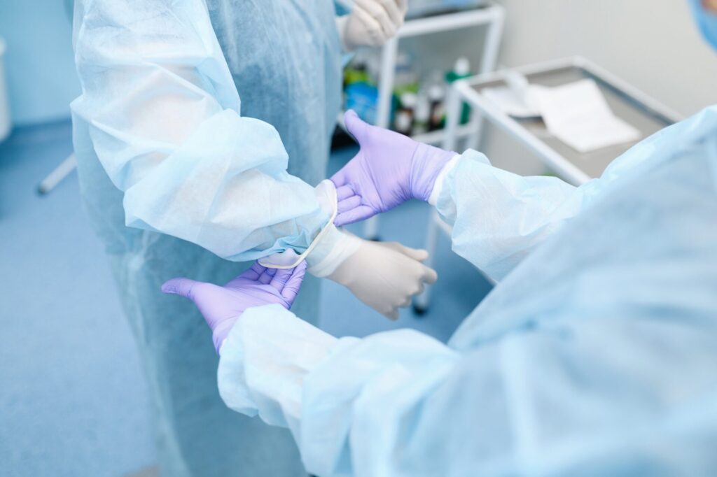 Female surgeon and assistant puts on a gloves