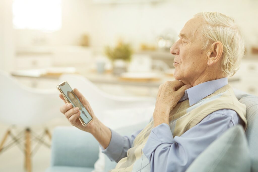 Pensioner looking at smartphone and chatting online with a doctor