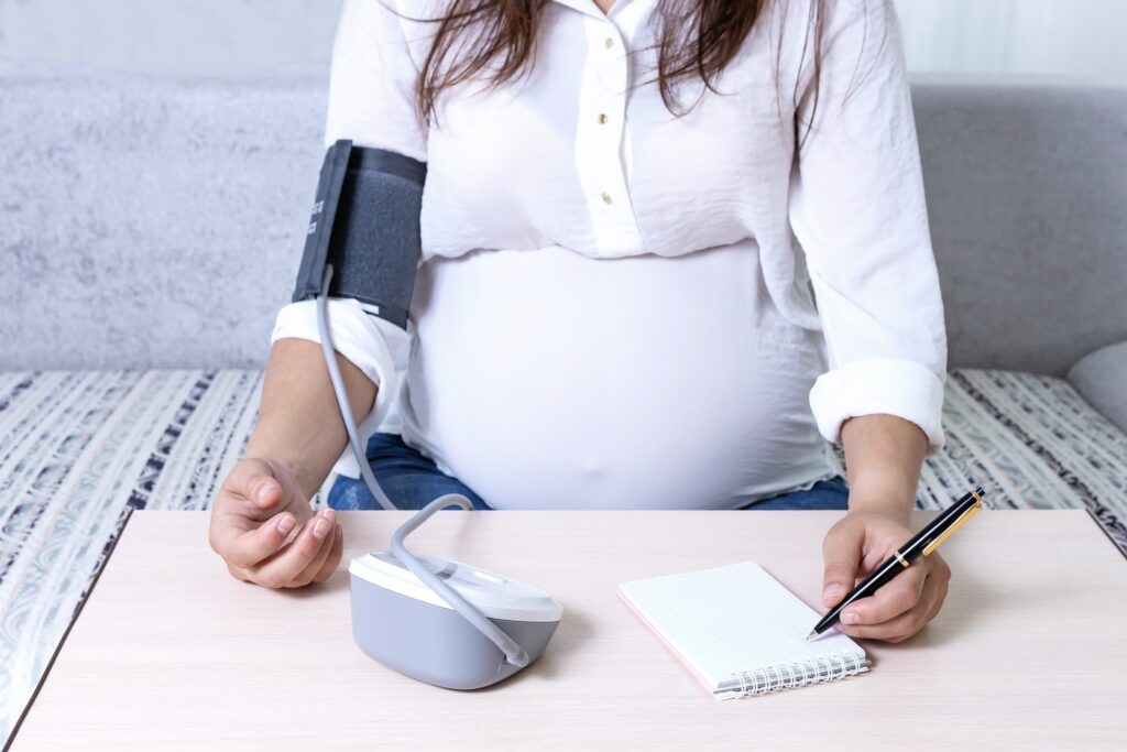 a pregnant woman measures blood pressure and writes the value in a notebook
