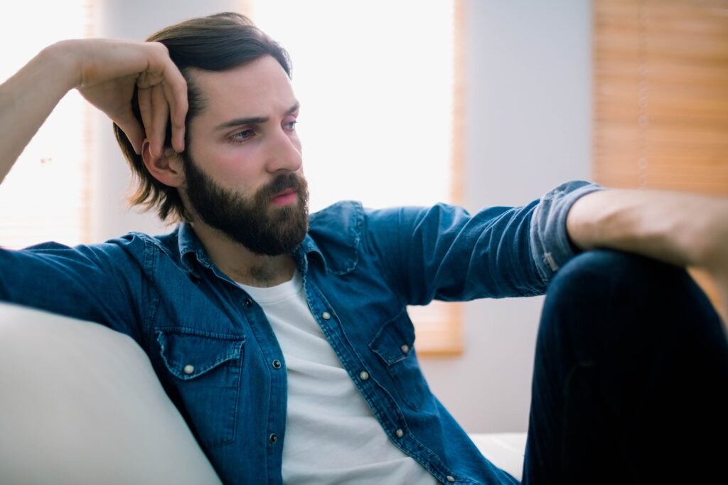 Unahppy man thinking on his sofa at home in the living room