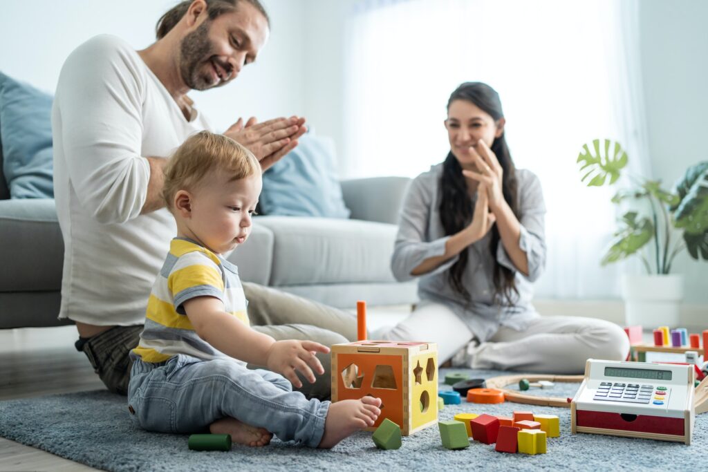 Caucasian happy loving parent spend time and play with baby toddler in living room at home