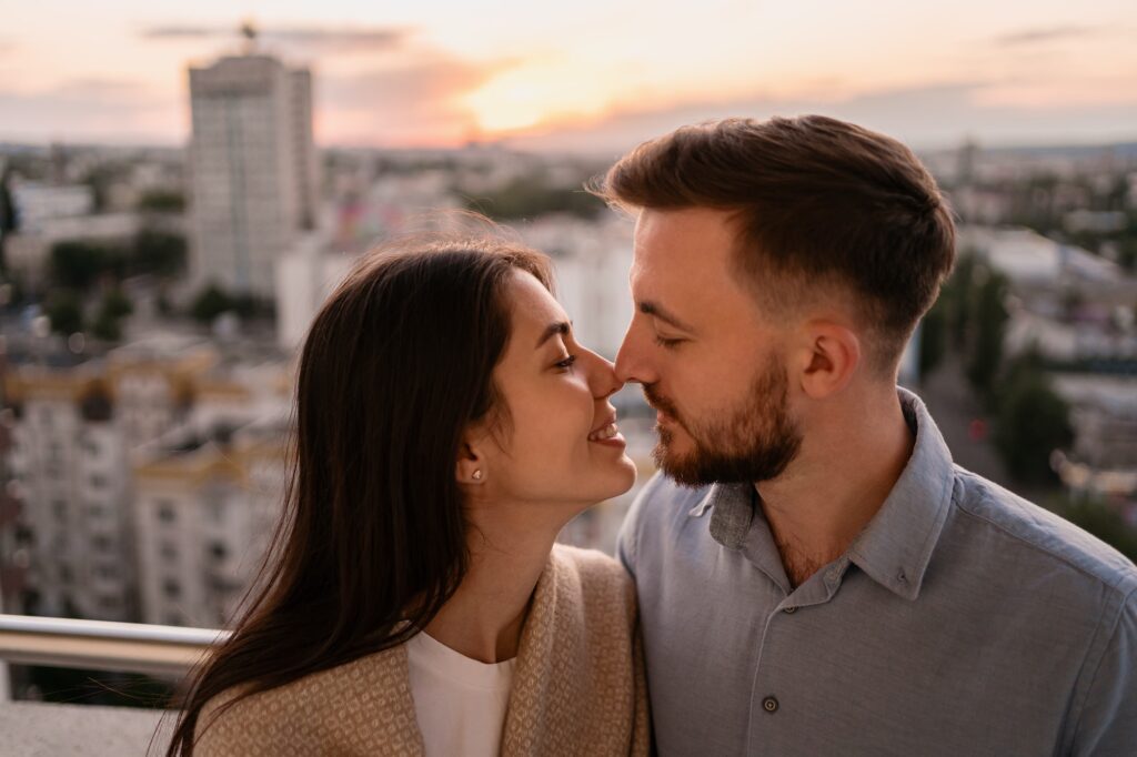 Man and woman on balcony at sunset in the city