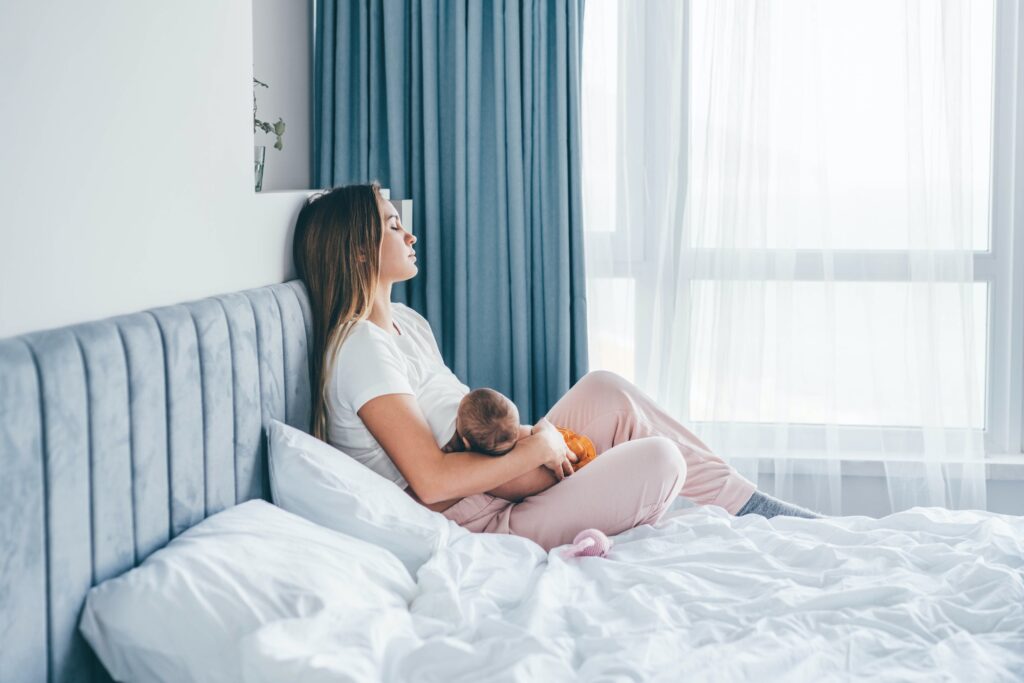 Young mother breastfeeds her baby girl at home.