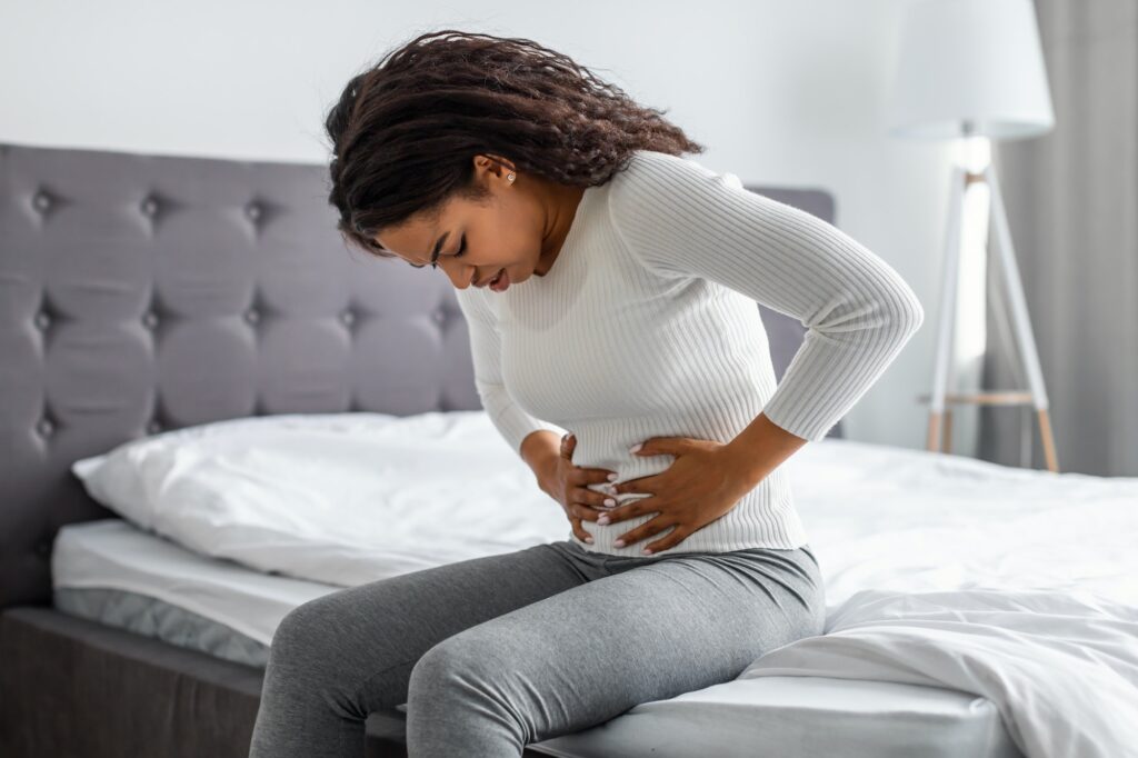 Black woman suffering from stomachache, touching her tummy