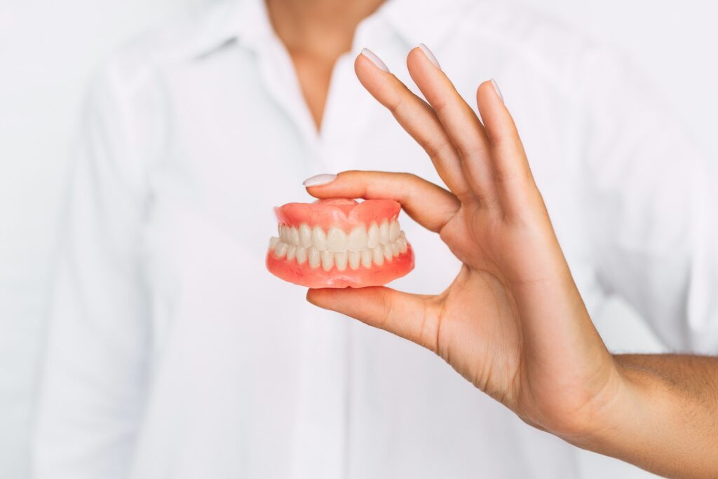 Dental prosthesis in the hands of the doctor close-up. Front view of complete denture