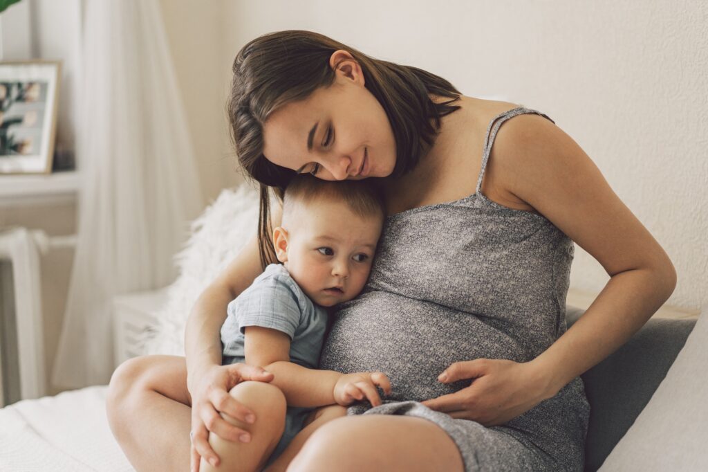 Young woman with her first child during second pregnancy. Motherhood and parenting concept.