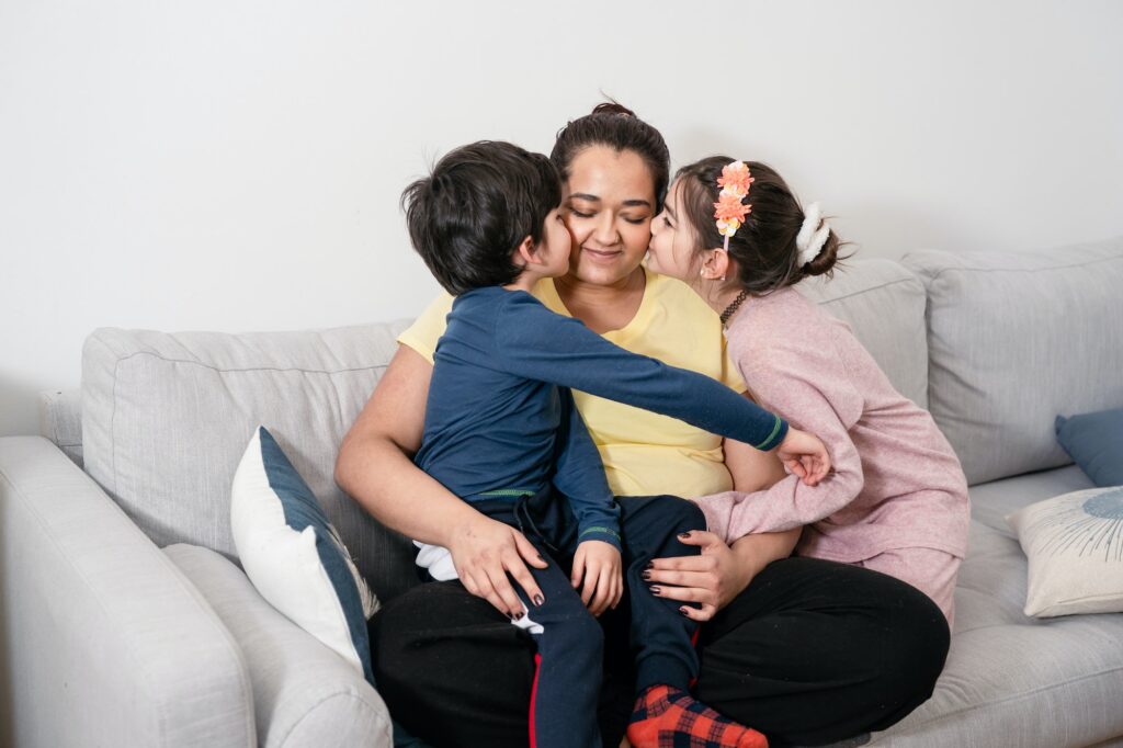 Mother and two kids sitting on sofa at home