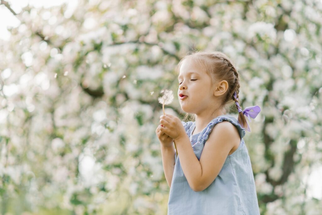 Beautiful child with dandelion flower. Happy kid having fun outdoors in spring park