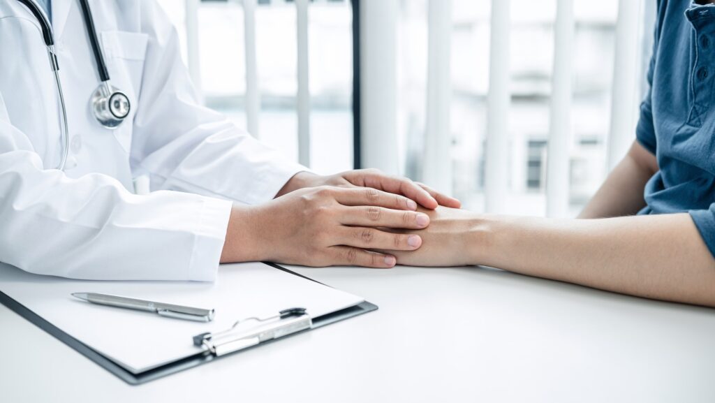 Doctor holding hands on patient about bad news at consulting room, to encourage, to supporting
