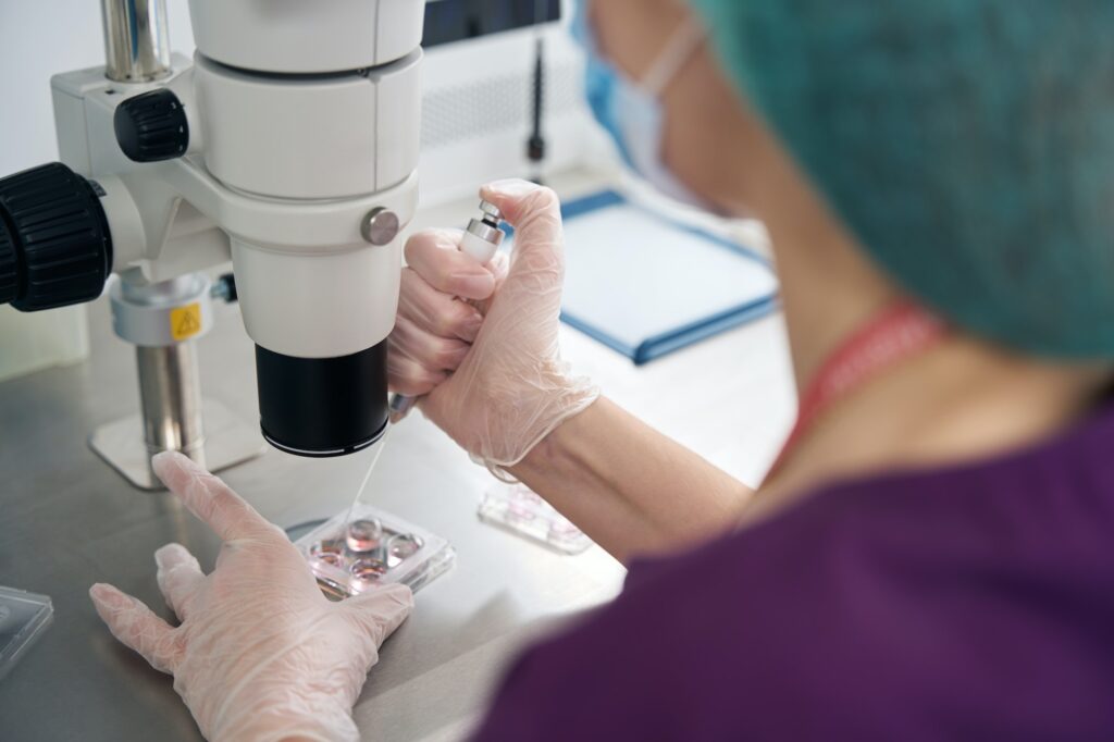 Embryologist examinesbiomaterial collected in embryo blocks under microscope