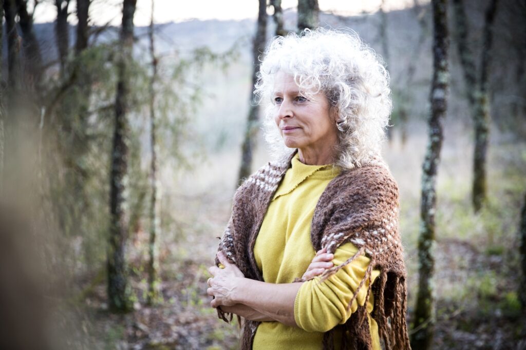 Mature woman standing in woodland with arms folded