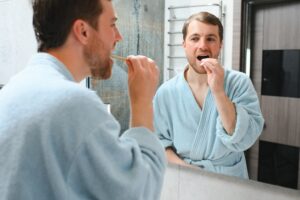 Brushing teeth in the morning. Rear view of handsome young beard man brushing his teeth