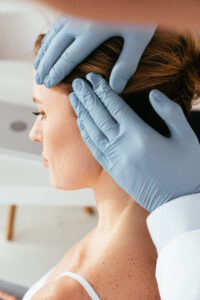 cropped view of dermatologist in latex gloves examining hair of patient in clinic