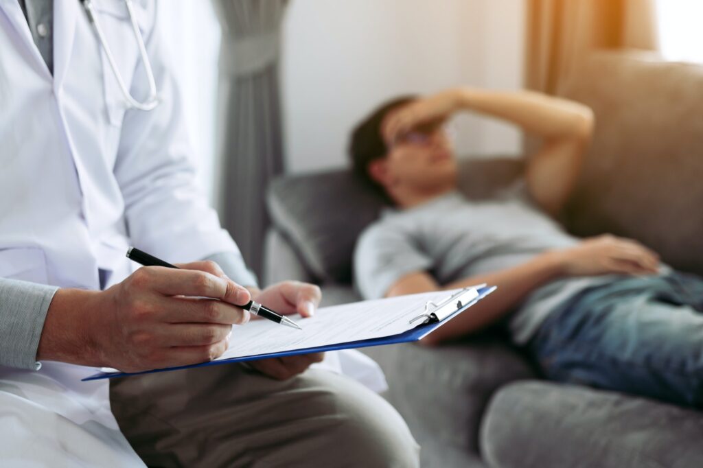doctor writing the pen and came to visit the patient at home while he headache