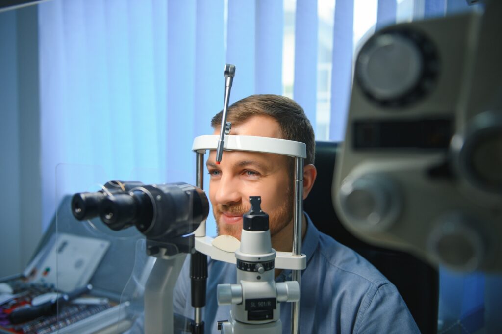 Handsome man getting an eye exam at ophthalmology clinic. Checking retina of a male eye close-up