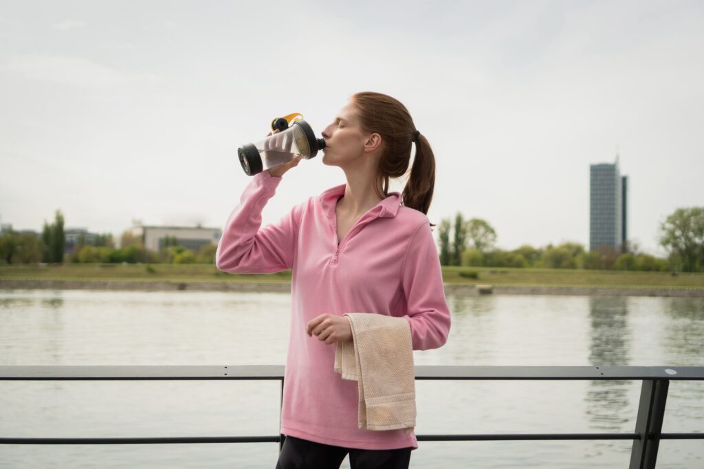 Healthy woman drinking water after exercising