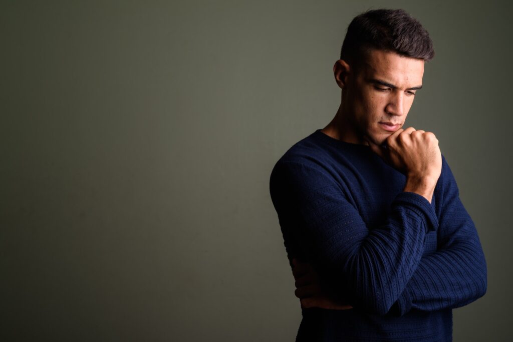 Young handsome man thinking against colored background