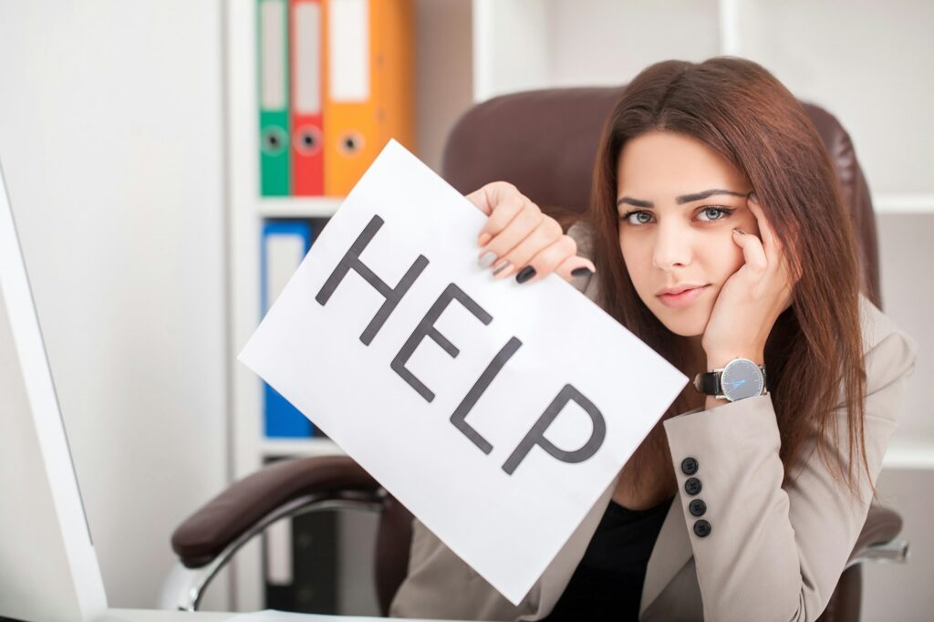 Attractive businesswoman in her 20s holding help sign