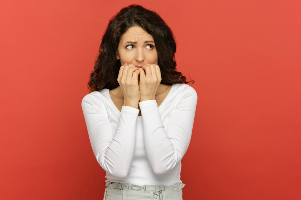 Worried stressed business woman scared of mistake at work bite finger nails in confusion and anxiety