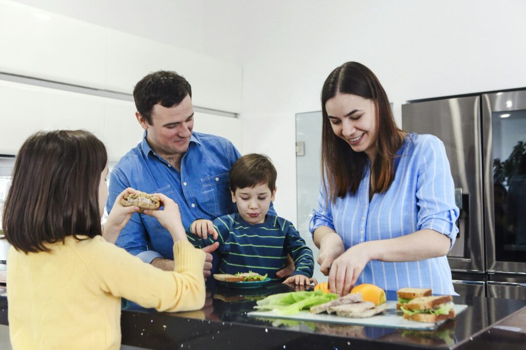 Cheerful family enjoying healthy breakfast together in kitchen at home weekend with little kids