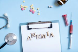 Anemia text with stethoscope, pills and syringe flat lay, top view