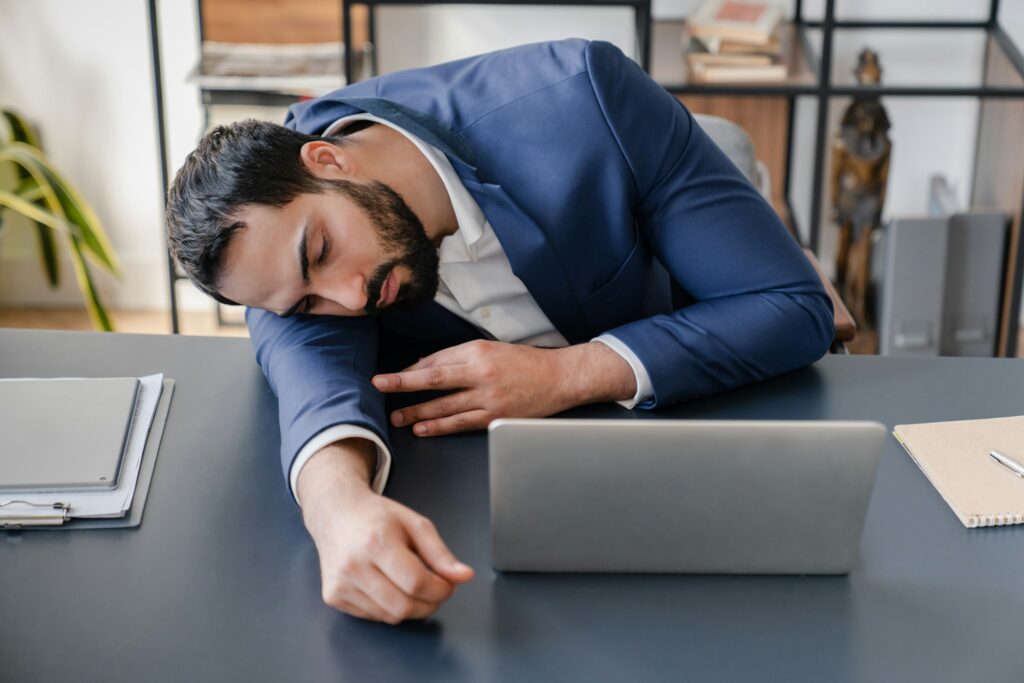 Tired exhausted overworked sleepy fatigued businessman sleeping napping at workplace