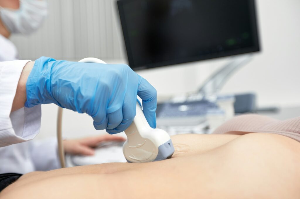 Female doctor gives the patient a female abdominal ultrasound. Ultrasound scanner in the hands of a