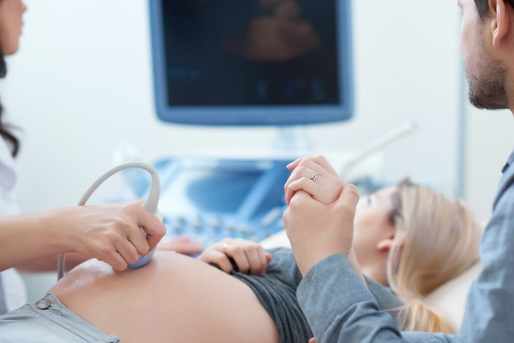Husband holding hand his wife during ultrasound diagnostic