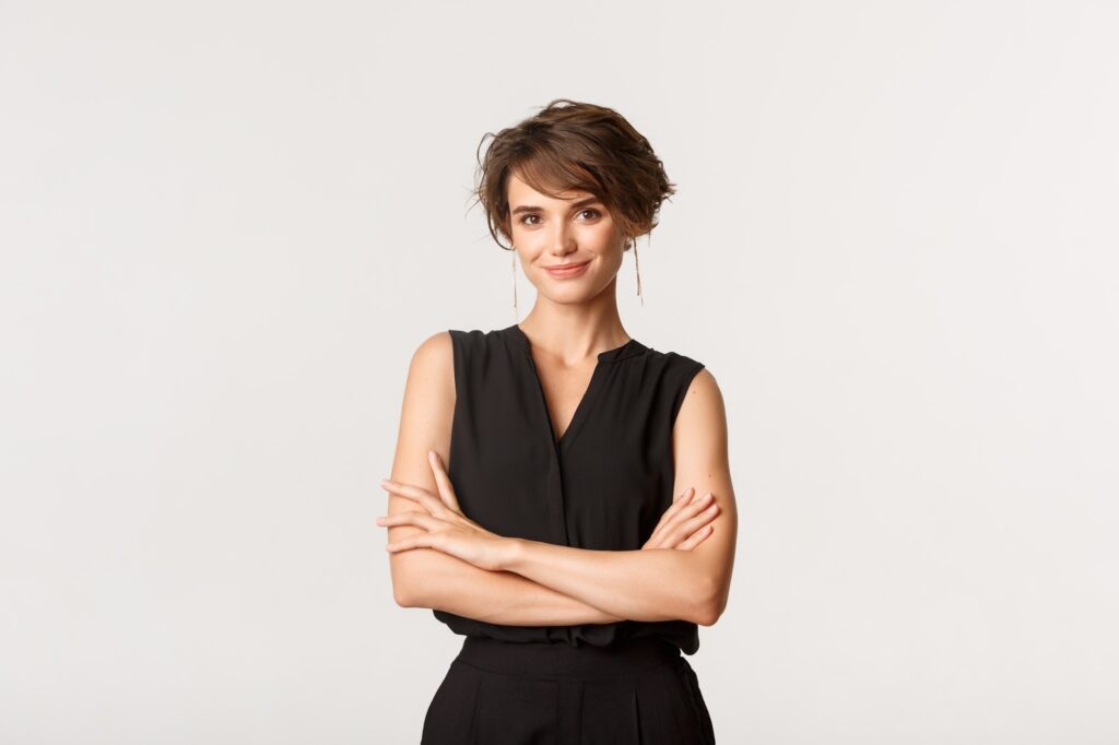 Young elegant woman standing in elegant clothes and smiling. Ambitious businesswoman looking at