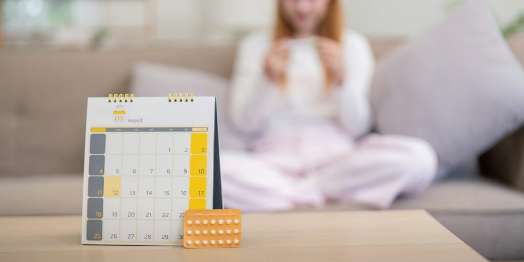 Birth control pills with calendar on table at home. Concept of contraception, family planning, and