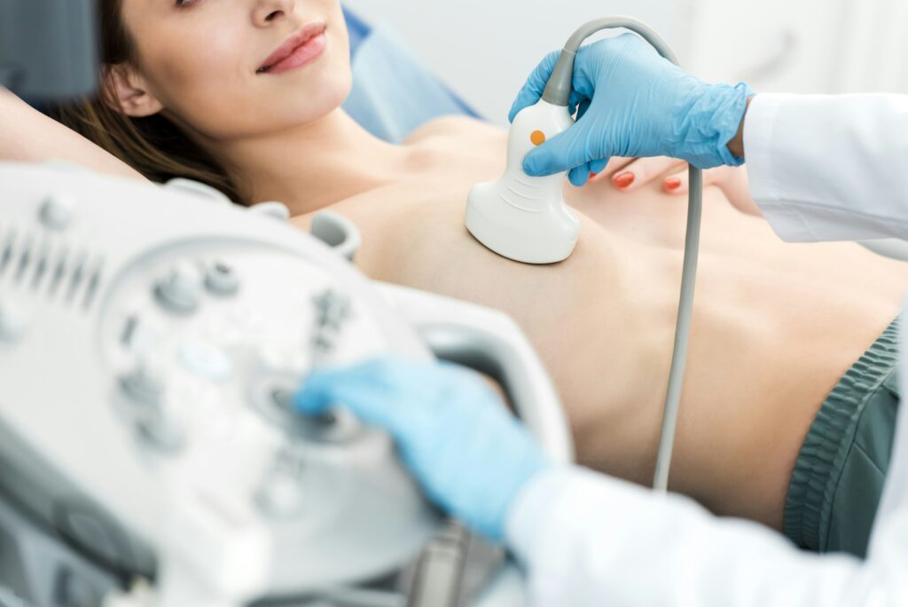 cropped view of doctor making breast examination for patient using ultrasound scanner