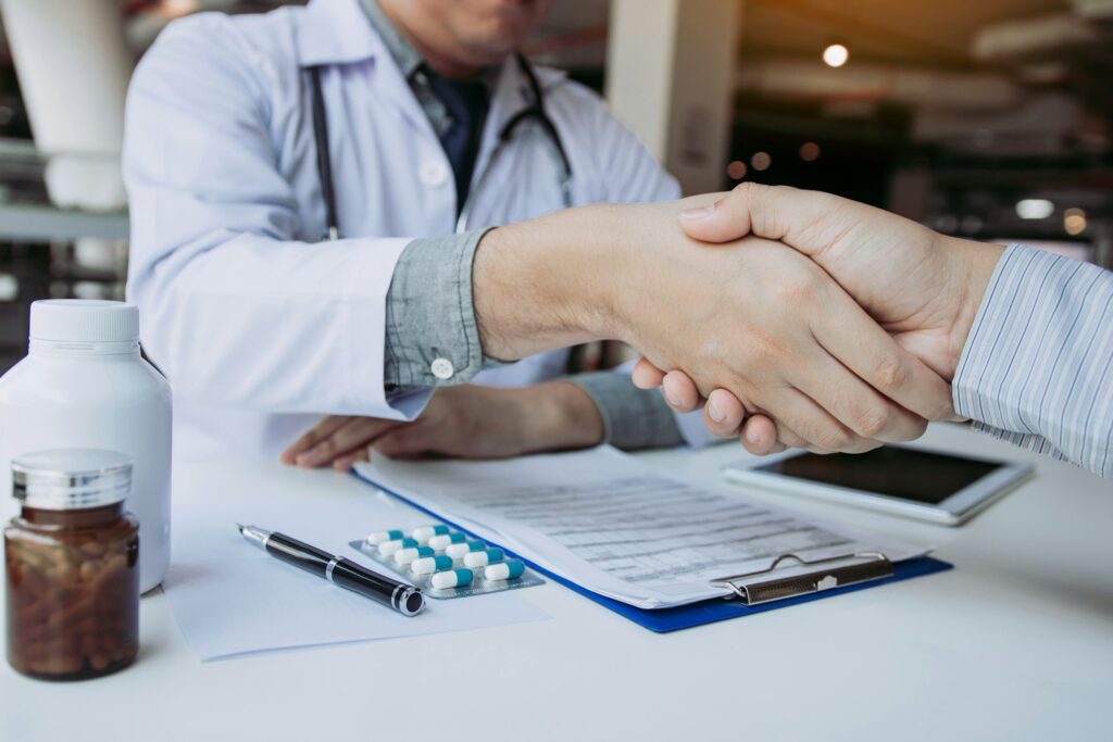 Doctor shaking hands with older patient in the clinic room.