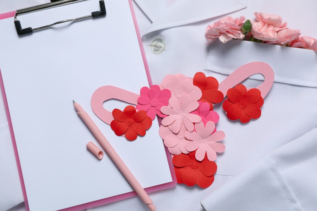 Doctors coat with flowers, clipboard, pen and uterus - Doctor Gynecologist