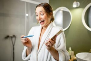 Happy woman with pregnancy test in the bathroom