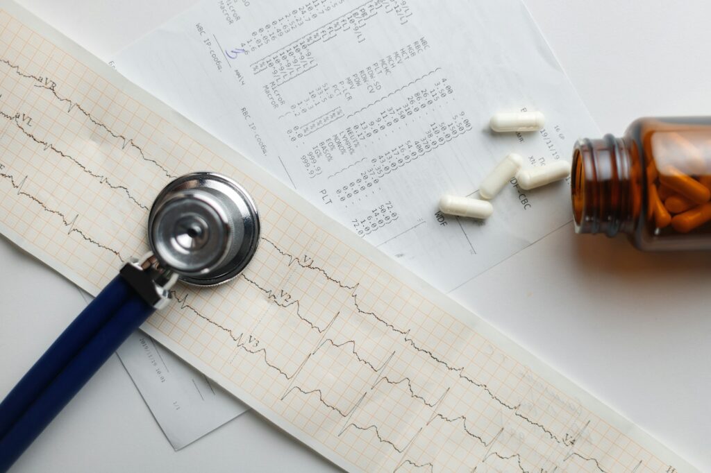 Stethoscope on cardiogram and blood tests with medicines in jar. Treatment of cardiovascular disease