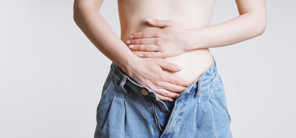 woman holding stomach with bellyache or period pains or indegestion
