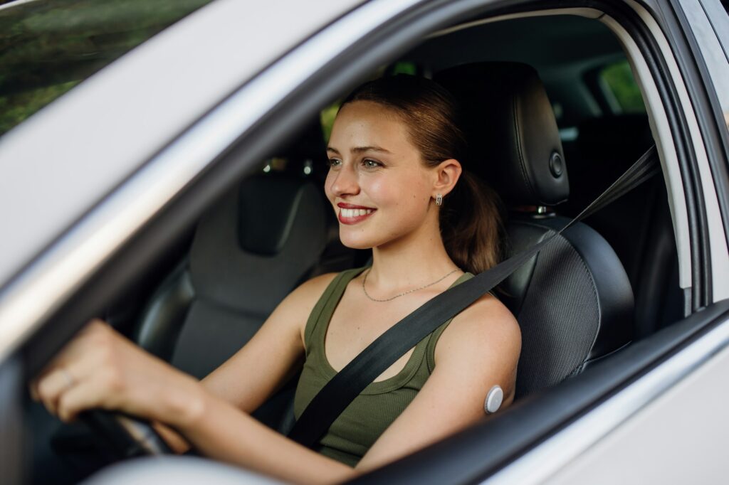 Woman with continuous glucose monitor driving car. Diabetic woman with CGM needs to raise her blood