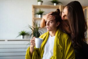 Worried woman cheks temperature of man at home. Fever, flu, illness, people concept