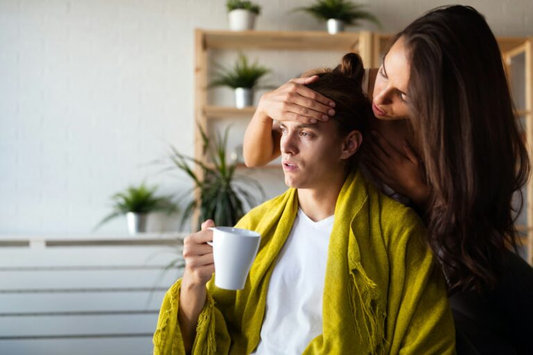 Worried woman cheks temperature of man at home. Fever, flu, illness, people concept