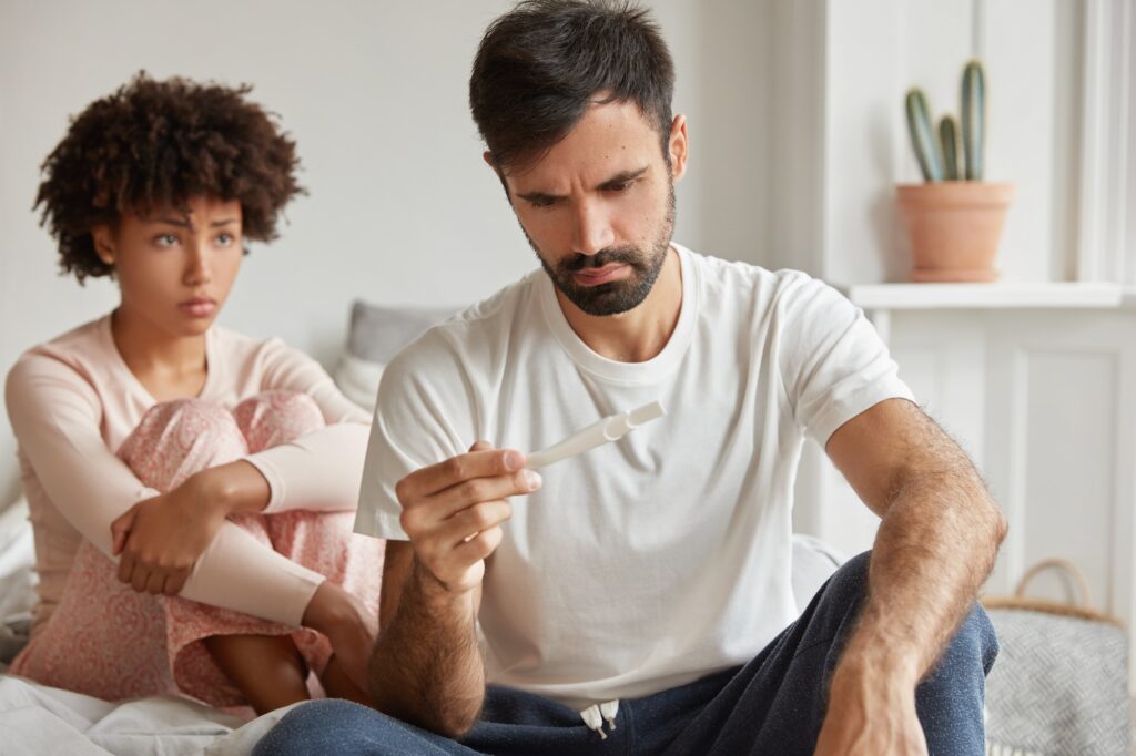 Contraception fail and unwanted pregnancy concept. Frustrated young family couple check pregnancy te