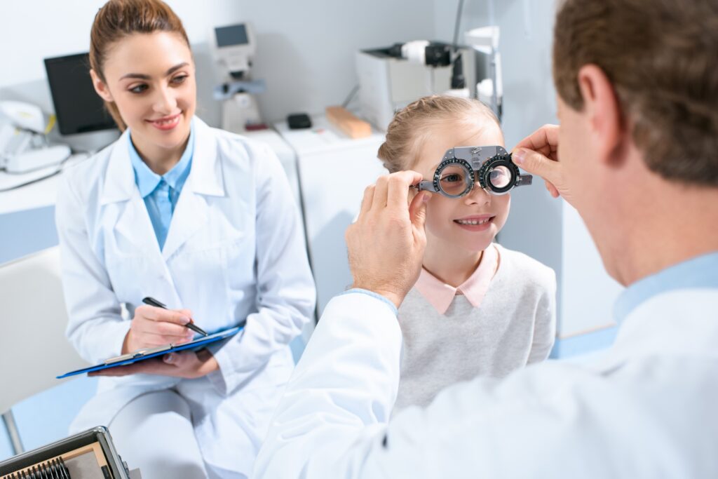 ophthalmologists examining kid eyes with trial frame and writing diagnosis