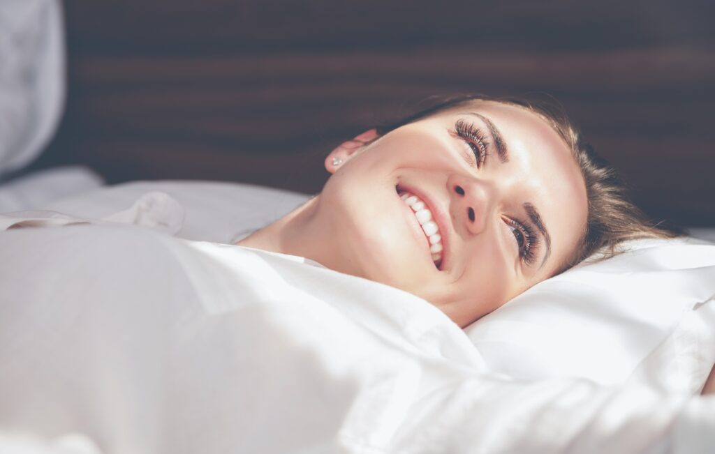 Pretty woman on bed in modern apartment smiling after wake up